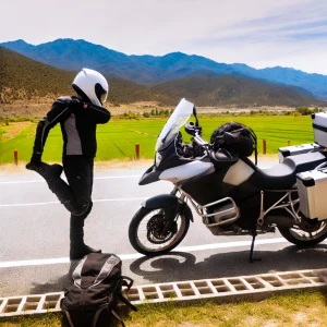 山々や広大な風景を背景に、バイクの横で休憩し、ストレッチをしているライダーの姿