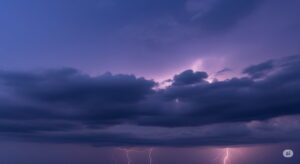 厚く暗い雲が広がり、遠くで稲光が光る空。